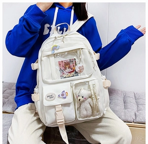 Detail of white nylon school backpack featuring transparent pockets and bear plush accessory
