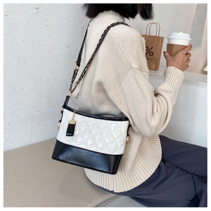 Detail of a quilted contrast crossbody bag with chain strap and elegant tassel charm