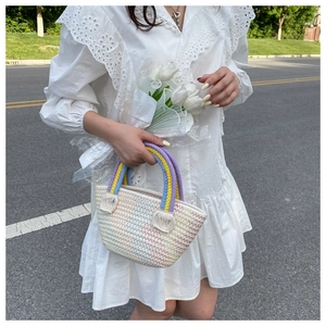 Detail of handmade rainbow woven straw bag with colorful handle and tassel accents