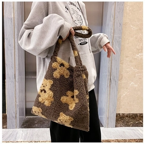 Detail of dark brown faux lamb wool tote bag with yellow bear pattern and shoulder strap