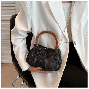 Detail of black rhinestone evening clutch bag with round wood handle and gold chain strap