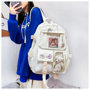 Detailed view of white multi-pocket backpack with bear plush and cute pins