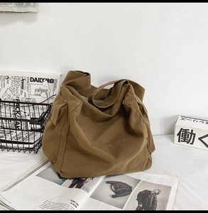 Detail of a khaki canvas crossbody bag with large side utility pockets and soft texture