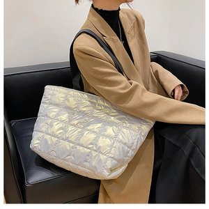 Chic silver quilted tote bag with black leather straps shown in a stylish urban setting