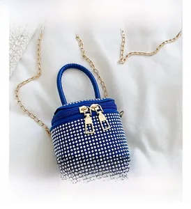 Detail of blue mini bucket bag with white rhinestones and golden metal chain strap