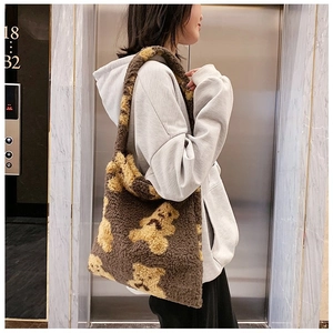 Detail view of large faux fur tote bag with cute bear pattern worn over the shoulder