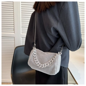 Close-up of a silver rhinestone evening bag with thick diamond chain on grey suit