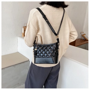Detail of black quilted shoulder bag with chain strap and structured leather base