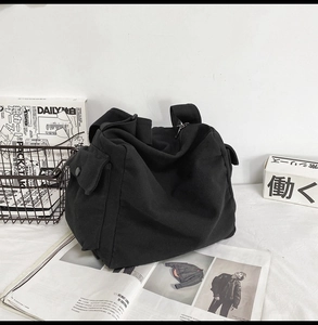 Detail shot of black washed canvas messenger bag with a functional side button pocket