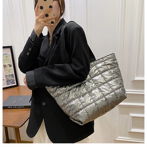 Close-up of a silver quilted puffer tote bag with metallic gloss finish and square stitching
