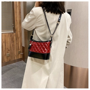 Detail of red and black quilted leather hobo bag with chain strap and fringe tassel