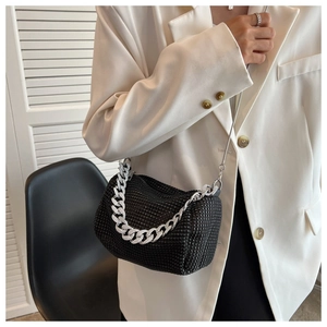Detail of black rhinestone crossbody bag with silver chain worn over a white suit