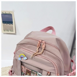 Detail view of pink nylon backpack with cute rainbow pin and transparent front pocket