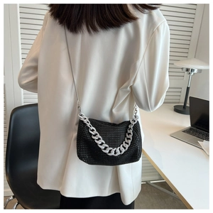 Detail of black rhinestone crossbody bag featuring silver metal chain and long shoulder strap