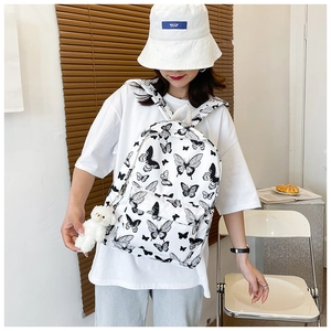 White butterfly print backpack for students featuring a plush bear charm and multiple pockets