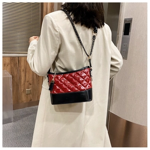 Close-up of a quilted red and black leather crossbody bag with a metal chain strap
