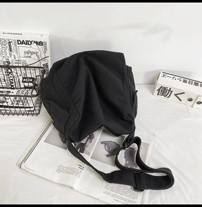 Macro shot of large black canvas messenger bag with wide strap on a white studio tabletop