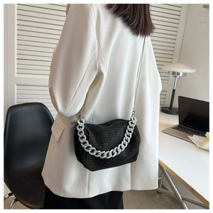 Detail of black rhinestone crossbody bag with silver chain and shimmering crystal texture