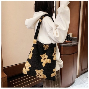 Detail of black fleece tote bag with yellow bear pattern worn over a white hoodie