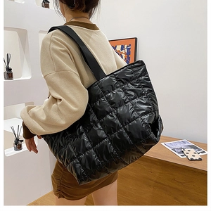 Fashionable black quilted puffer tote bag in glossy nylon shown on model's shoulder