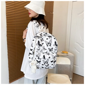 Close-up of butterfly print backpack with a cute white plush bear keychain accessory