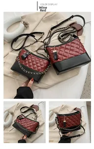 Detail view of wine red quilted hobo bag with gold chain strap and stylish black tassels