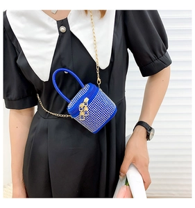 Close-up of mini blue rhinestone box bag with gold chain strap worn by a model
