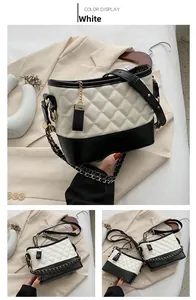 Detail view of white quilted crossbody bag with black trim and gold chain strap