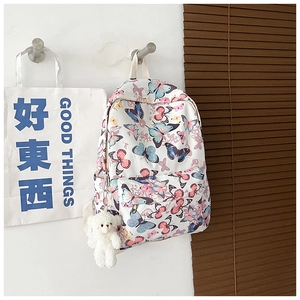 Detail view of white canvas backpack with colorful butterfly print and cute bear pendant