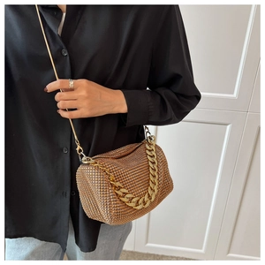Close-up of golden rhinestone chain bag featuring a metallic handle and long shoulder strap