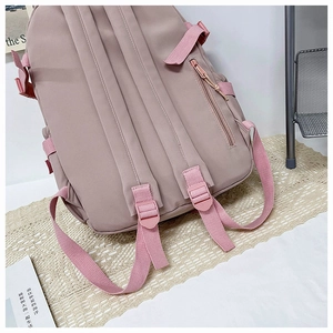 Detail of pink nylon backpack featuring adjustable straps and a secure rear zipper pocket