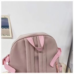 Detailed back view of pink nylon backpack showing adjustable padded straps and side pockets