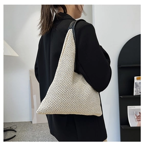 Detail of minimalist cream woven tote bag with contrast black faux leather straps