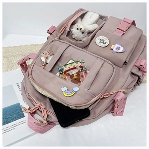 Detail view of pink nylon school backpack with multi-pockets and cute teddy bear pendant