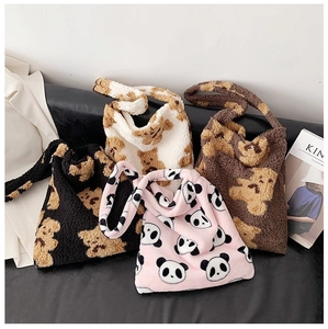 Macro shot of four plush tote bags with bear and panda prints on a black bench