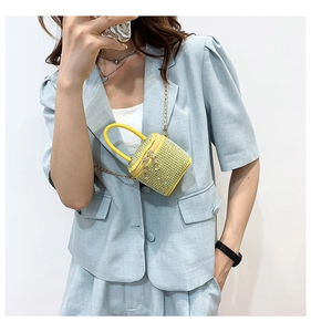 Detail of yellow mini crossbody bag with sparkly rhinestones and a metal chain strap