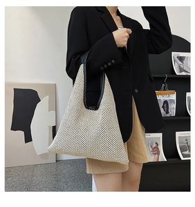 Detail of minimalist straw tote bag with black leather handles and woven triangle design