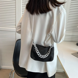 Elegant black rhinestone crossbody bag with silver chain worn by a model in white blazer