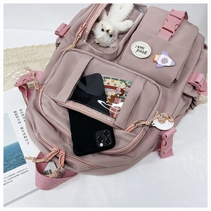 Detail view of pink nylon backpack with multi-pocket design and cute bear charm