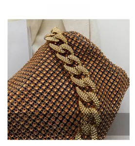 Close-up of amber rhinestone evening bag with chunky gold chain handle detail