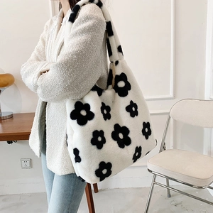 Detailed view of the white plush tote bag with black floral pattern worn by a model