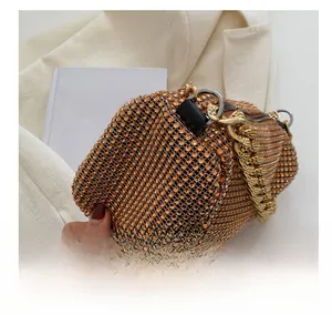 Detail of amber orange handbag with sparkling crystals and thick gold chain strap