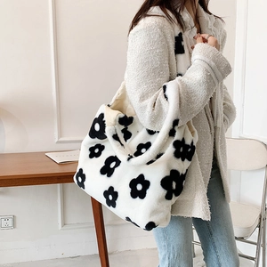 Close-up of white plush tote bag featuring black floral patterns and soft faux fur texture