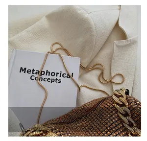 Detailed macro view of the amber rhinestone surface and golden chain of the shoulder bag