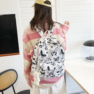 White butterfly print backpack with plush bear charm worn by student in bright room