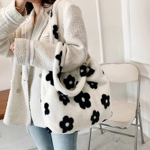 Detailed texture of white plush tote bag with black floral pattern on a shoulder strap