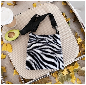 Detail of soft zebra print plush tote bag with adjustable black strap and fuzzy texture