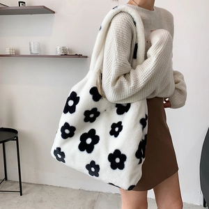 Detailed view of soft plush tote bag with black daisy pattern on white faux fur fabric