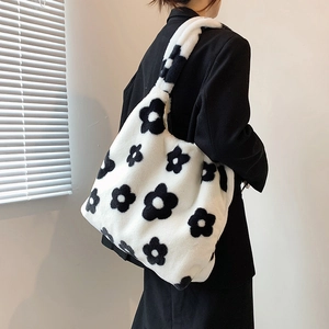 Detail of soft plush tote bag with black flower pattern shown on model shoulder