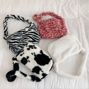 Detailansicht verschiedener Plüsch-Unterarmtaschen mit Kuh-, Zebra- und Leopardenmustern